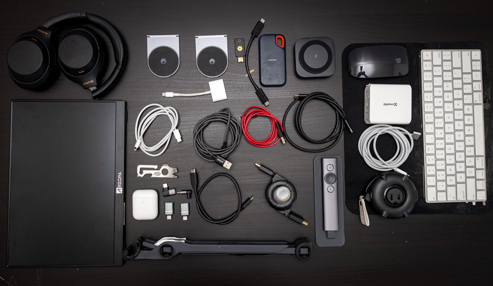 My desk setup gear laid out: keyboards, mice, webcam, headphones, SSD, chargers, presenter, and stands